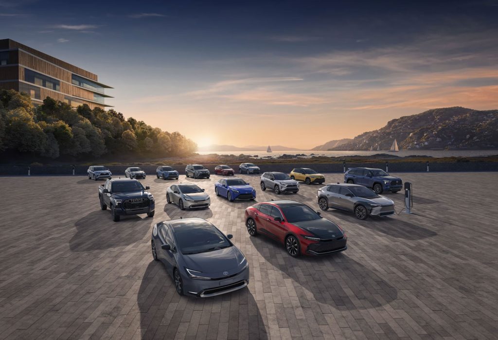 A lineup of various Toyota vehicles parked outdoors with a scenic view at sunset.