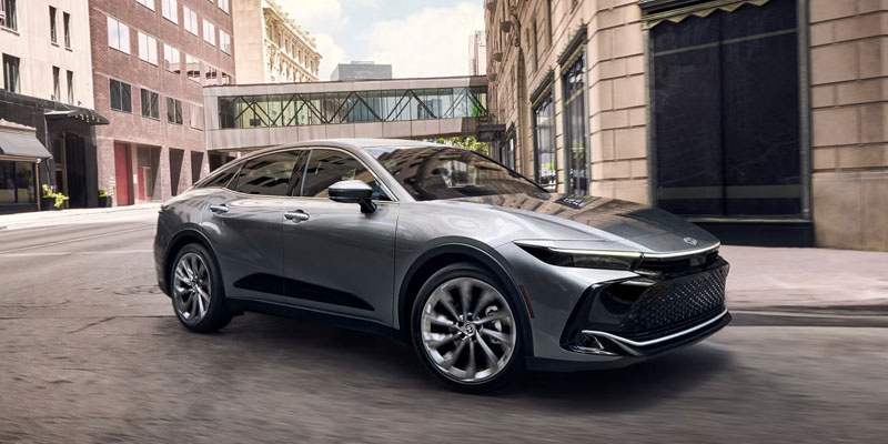 This is a sleek, modern 2026 Toyota Crown sedan driving through an urban setting.