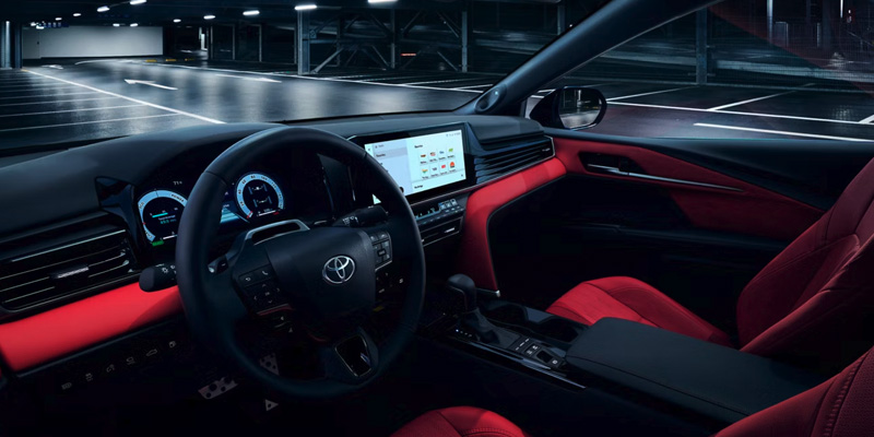 Toyota car interior with red seats, digital display, and steering wheel.