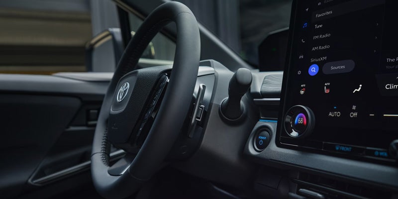 Toyota C-HR interior close-up of steering wheel and infotainment screen.