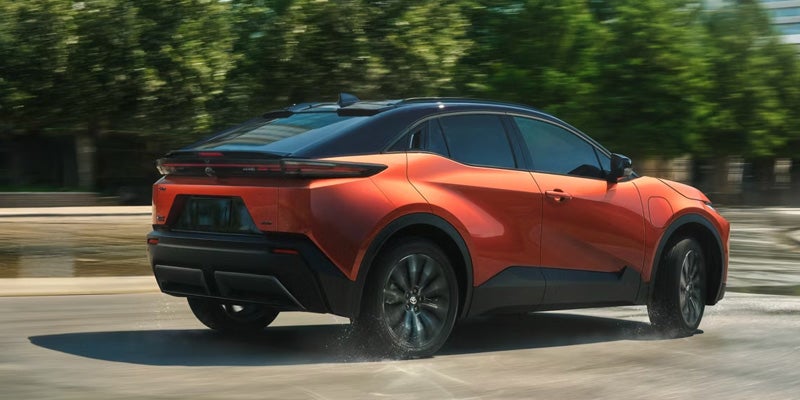 Rear three-quarter view of a 2026 Toyota C-HR driving on a road.