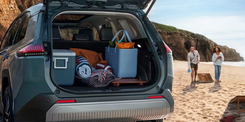 SUV cargo area packed with beach and camping gear at a seaside location.