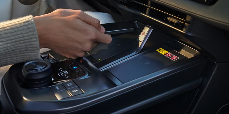 Hand placing smartphone on car wireless charging pad.